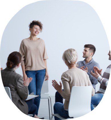 a woman standing in front of a group of people clapping