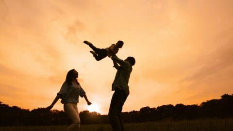 a man and woman playing with a child in a field after having Counseling for parents at REACH Ohio