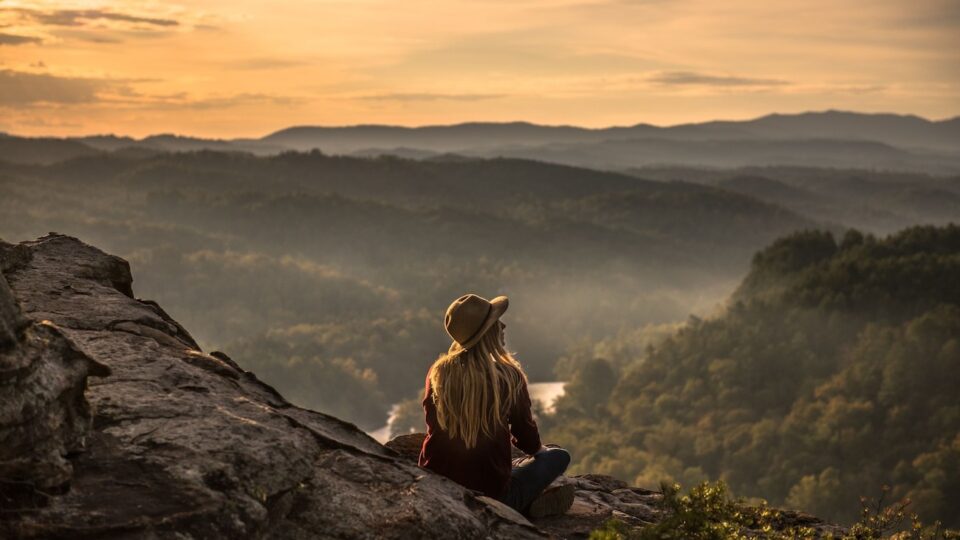 a woman sitting on a rock looking at a valley symbolizing new beginnings and hope. REACH, Ohio