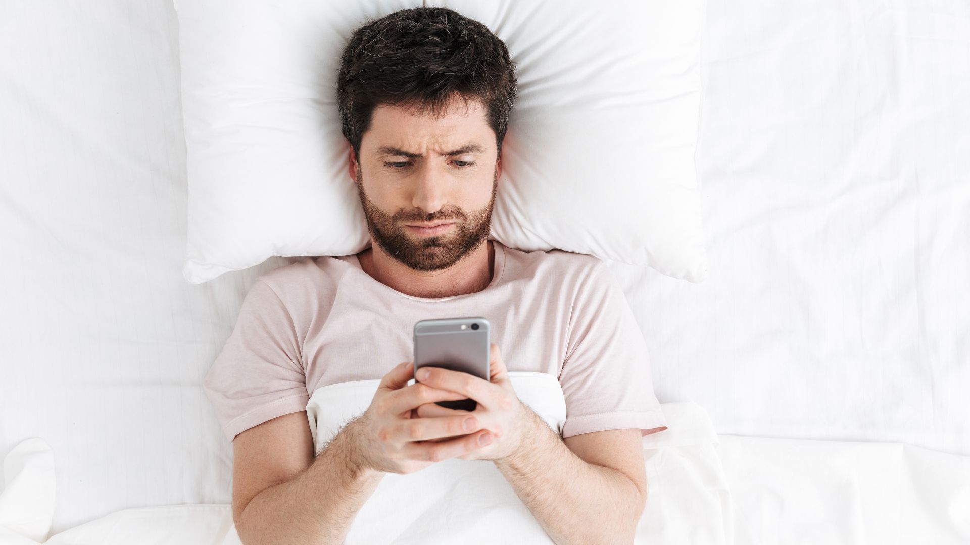 a man lying in bed looking at his phone