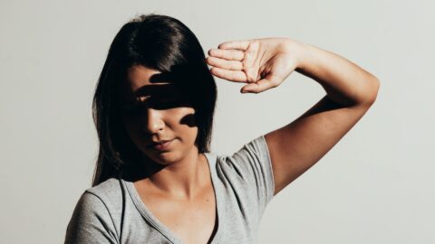 A woman with her hand raised to her forehead, symbolizing the barriers to overcome when looking for a psychiatrist.