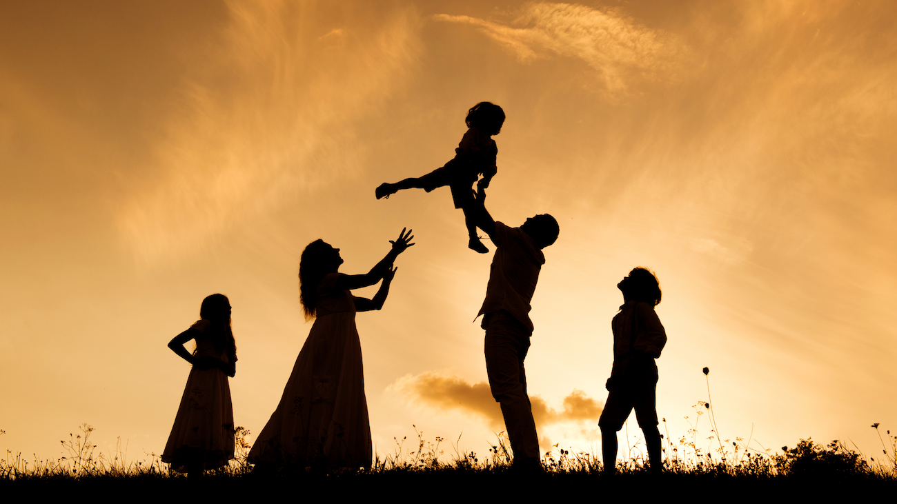 Silhouette of a family enjoying a moment together at sunset, with a man playfully tossing a child into the air, symbolizing connection and joy. Perfect representation of the positive impact of family therapy in strengthening relationships and fostering support