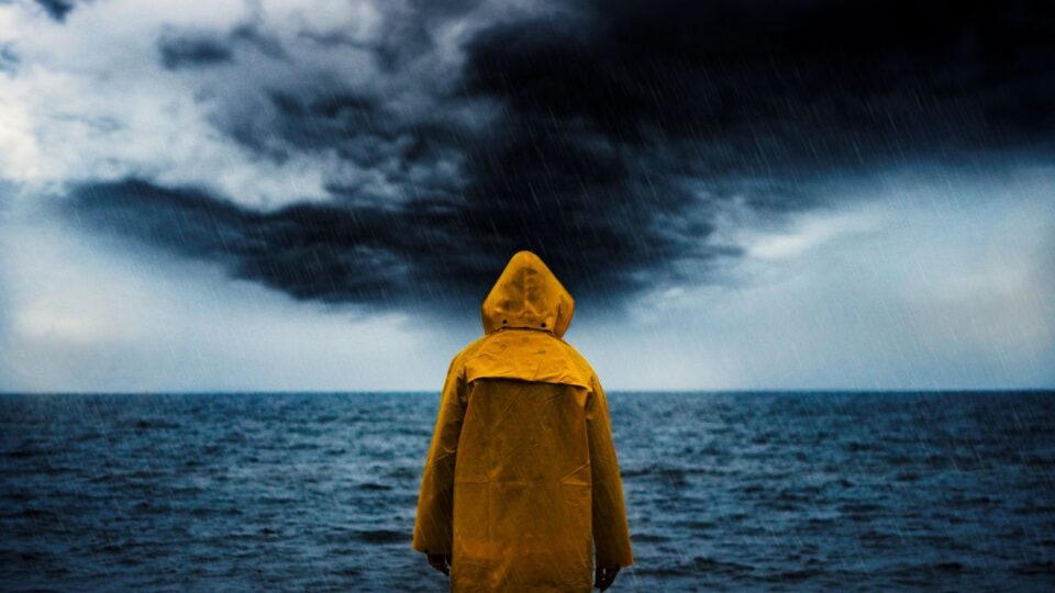 A person in a yellow raincoat standing in the rain, symbolizing the challenges of living with bipolar disorder and the hope offered by bipolar disorder supportive therapy