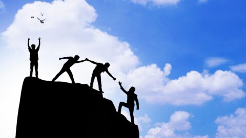 Silhouette of people helping each other climb a mountain rock at sunset, symbolizing support, personal growth, and overcoming challenges—relevant to the question “Do I have a drinking problem” and the journey toward recovery