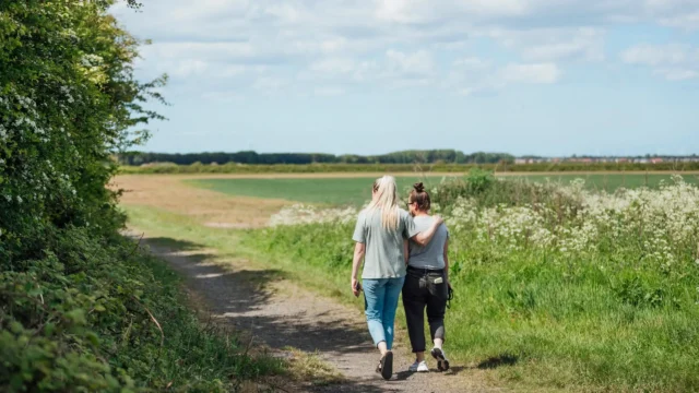 Two people walking together down a peaceful path in nature, symbolizing support and recovery while exploring the question of how long major depressive disorder lasts.