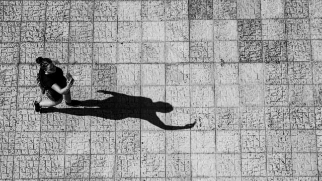 Black and white photo of a person walking on a tiled path with a long shadow, symbolizing self-reflection and hope in overcoming treatment-resistant depression (TRD) in Ohio