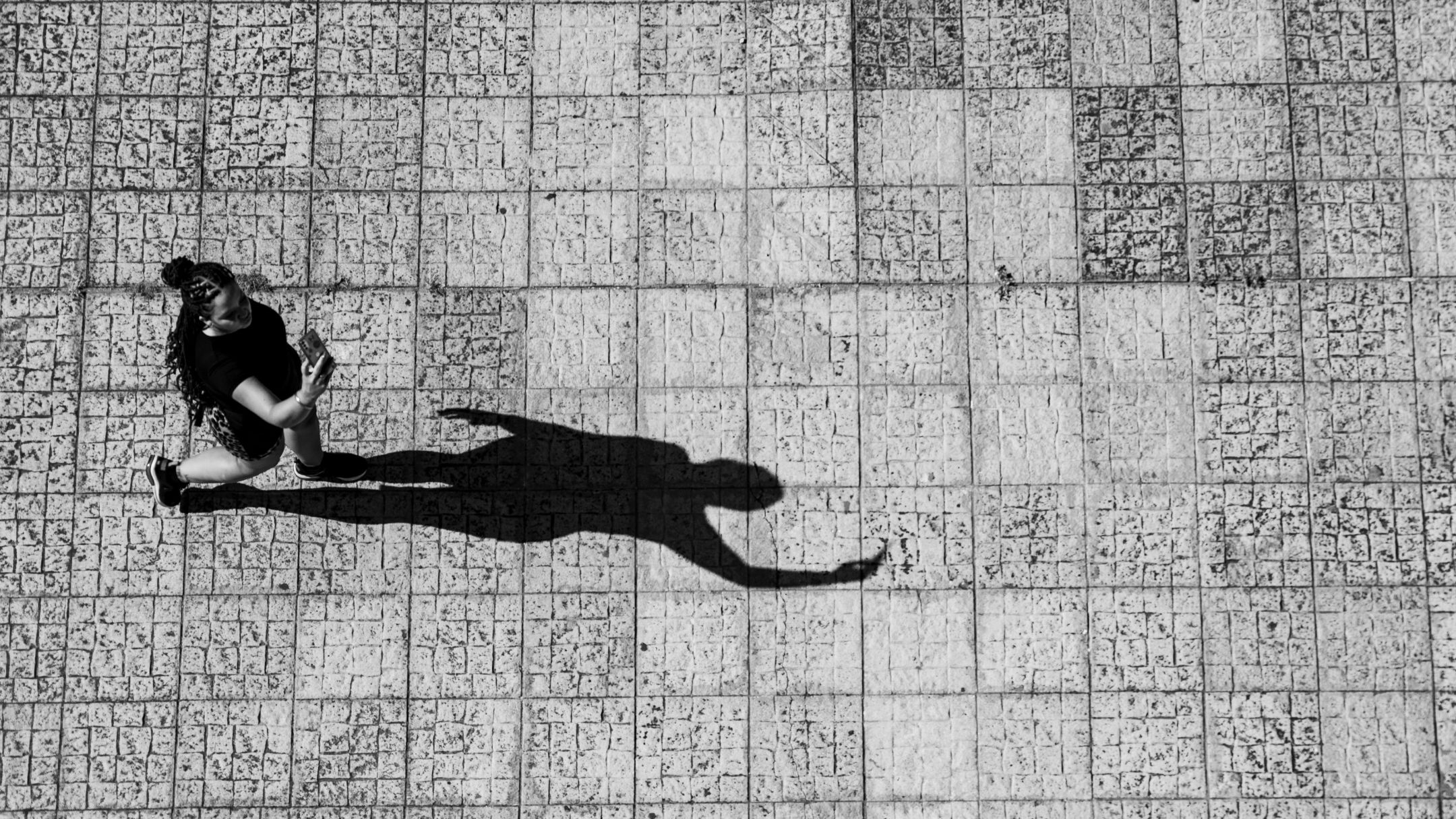 Black and white photo of a person walking on a tiled path with a long shadow, symbolizing self-reflection and hope in overcoming treatment-resistant depression (TRD) in Ohio