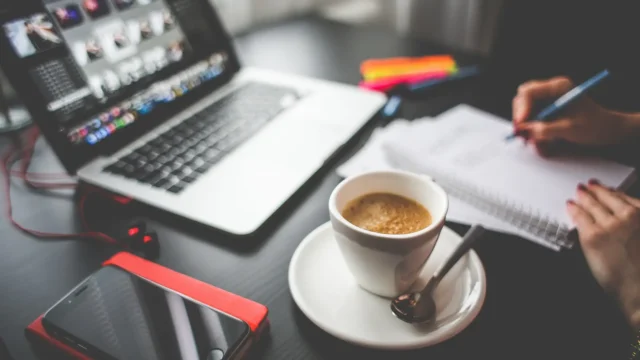 Workspace with a laptop, notebook, phone, and coffee cup, symbolizing research into the Best Treatment for Autism and how ongoing support helps autistic adults in daily life and work.