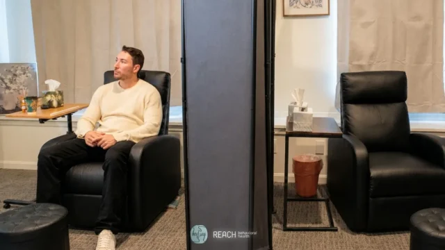 Patient seated in a private mental health treatment room during IV Ketamine vs Spravato treatment, with comfortable recliners and privacy screens.